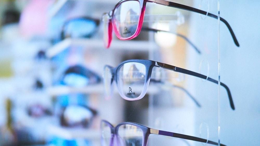 In einem Optikergeschäft sind Brillen in verschiedenen Stilen und Farben ausgestellt.