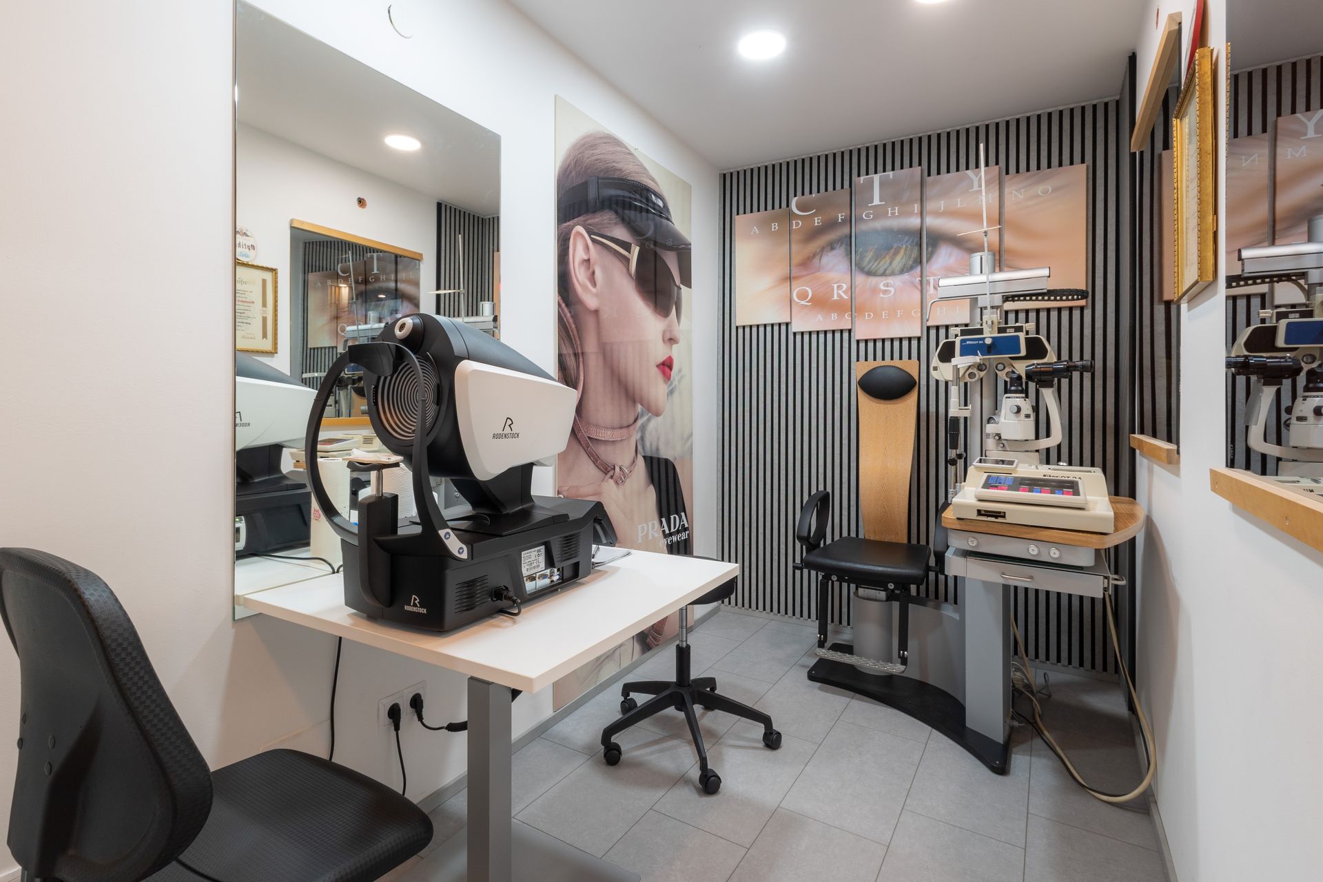 Optometriepraxis: Untersuchungsraum mit Geräten, Stühlen und einem stilvollen Wandbild mit Augenmotiv.