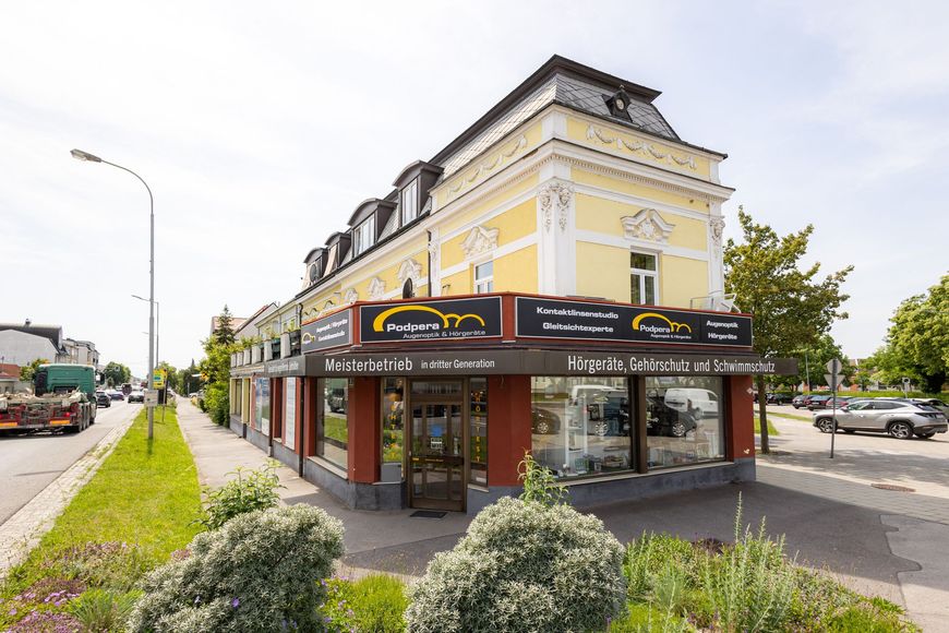 Ein gelbes Gebäude mit einem Autogeschäft, Straßenansicht, sonniger Tag.