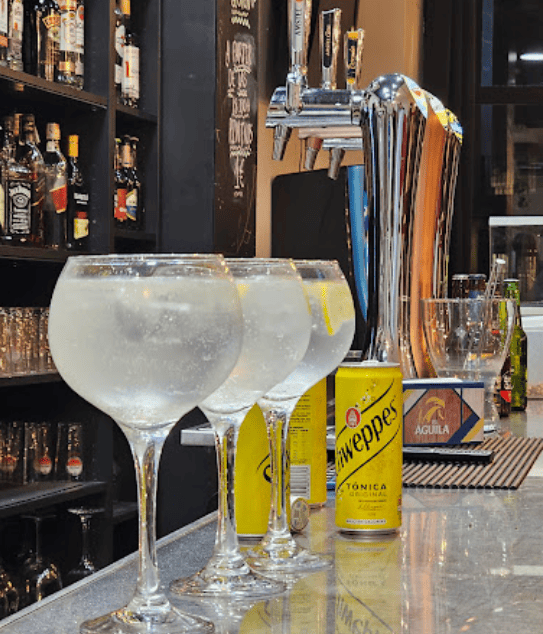 Una lata de Schweppes se encuentra junto a una fila de copas de vino.