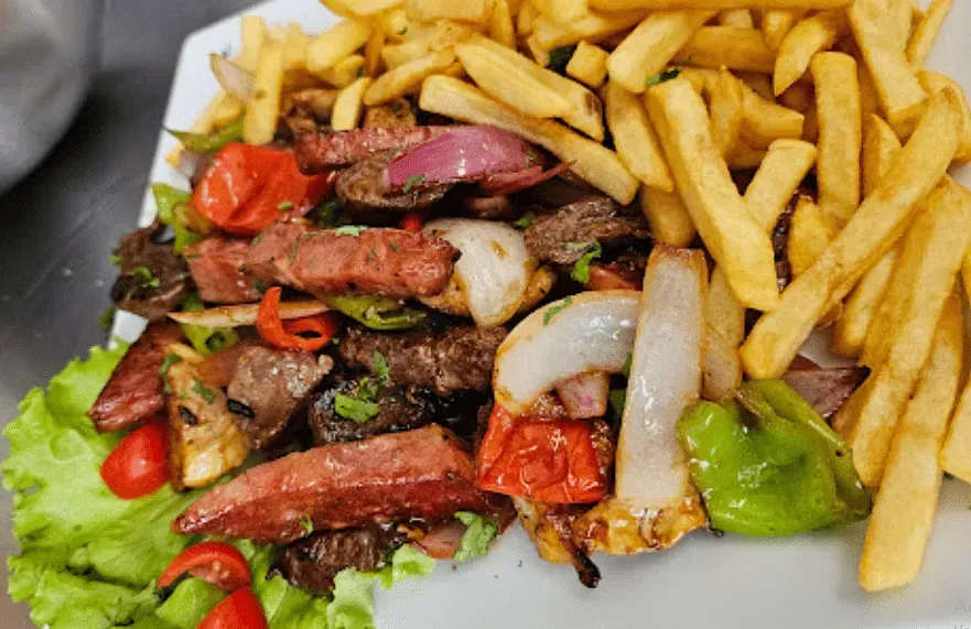 Un plato de comida con patatas fritas y carne en una mesa.