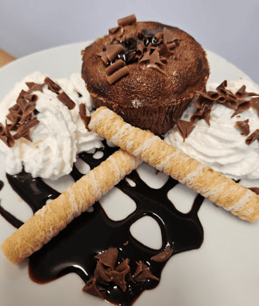 Un pastel de chocolate con crema batida y virutas de chocolate en un plato blanco
