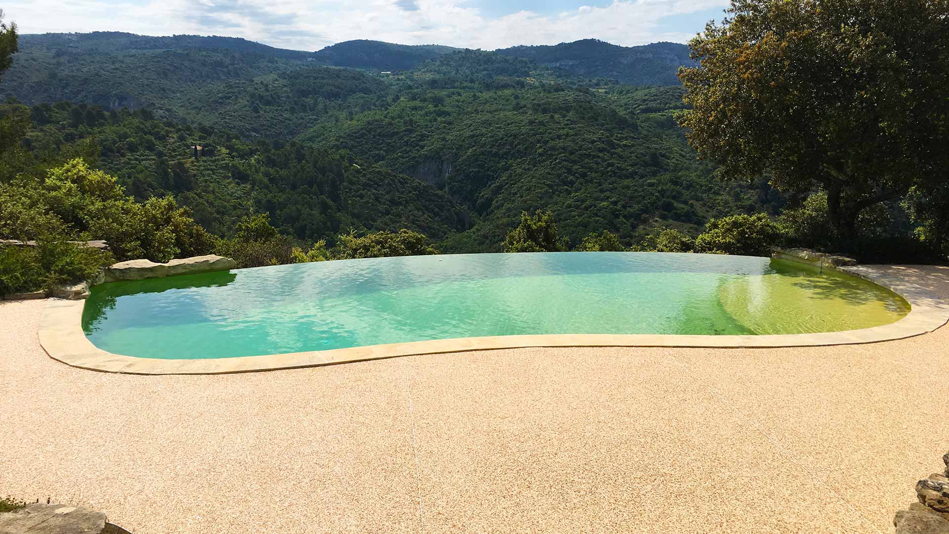 Superbe piscine à débordement donnant sur des collines arborées.