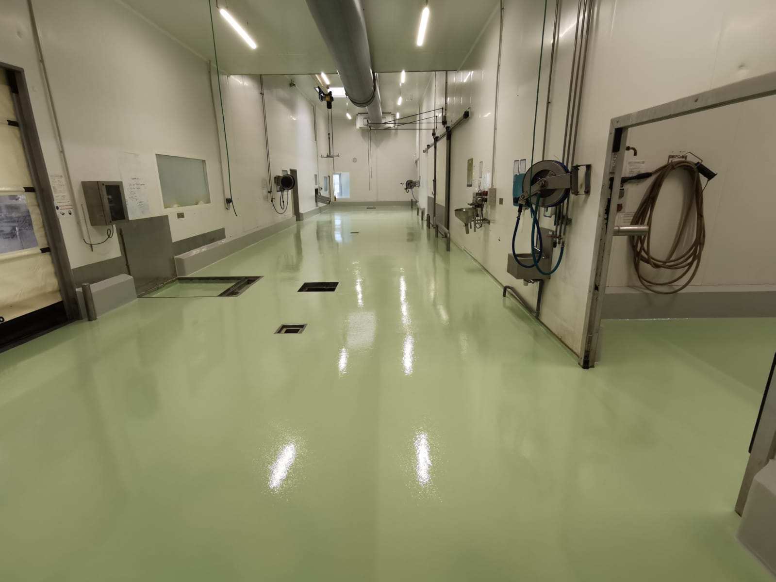 Sol en résine verte brillante dans un espace intérieur industriel avec des équipements.