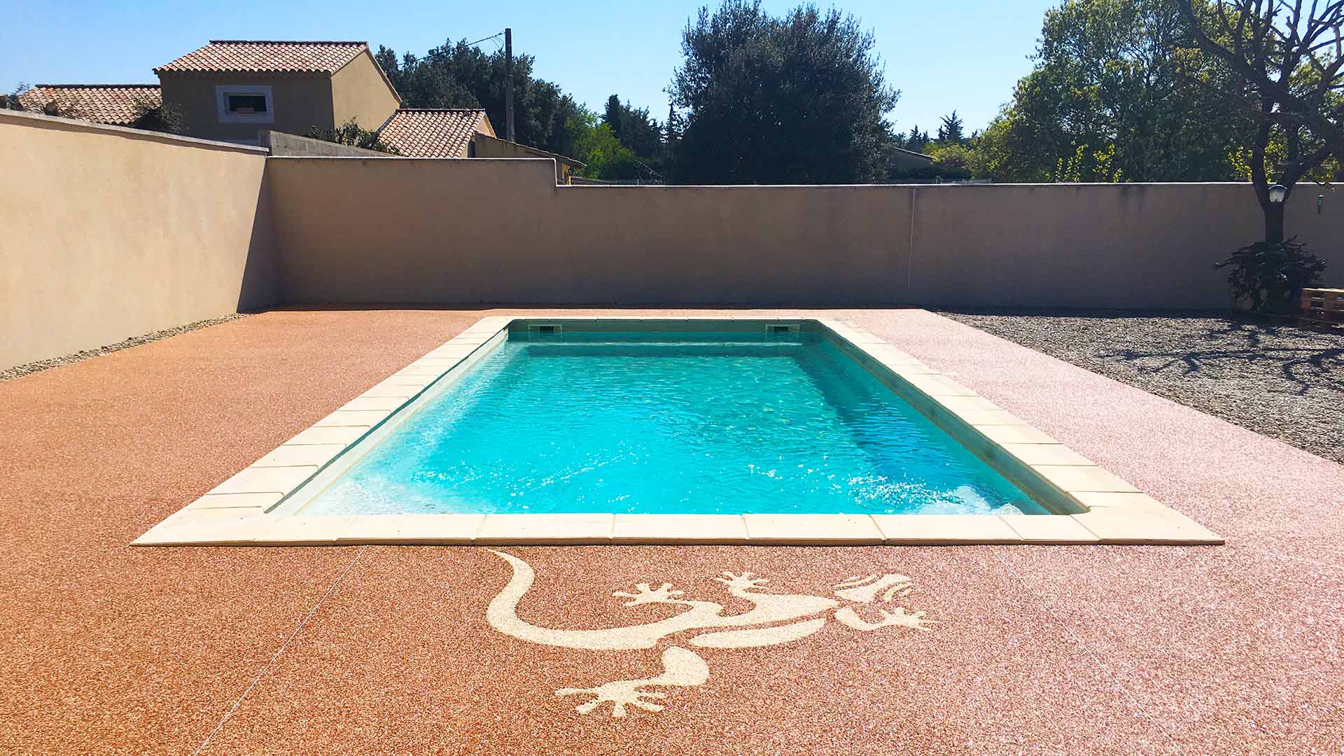 Motif de lézard sur résine ocre devant piscine creusée.