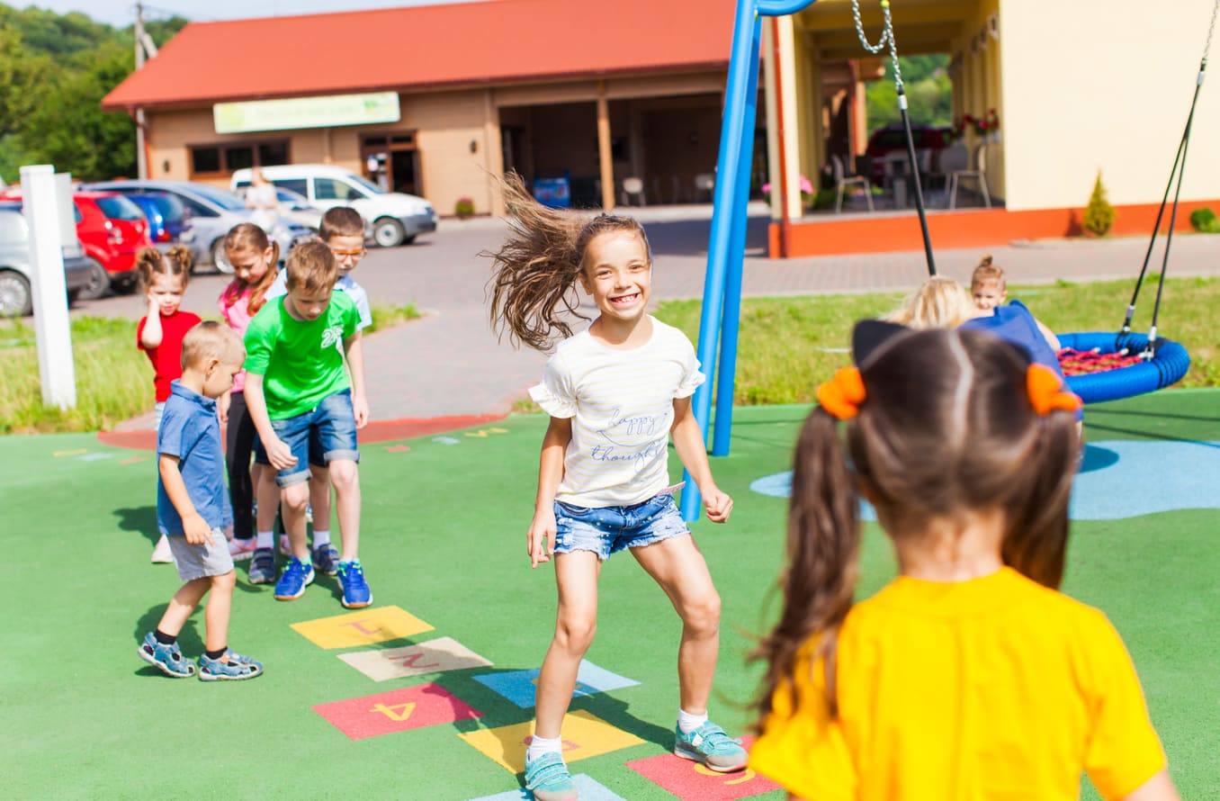 Enfants jouant à la marelle dans cour d'école.