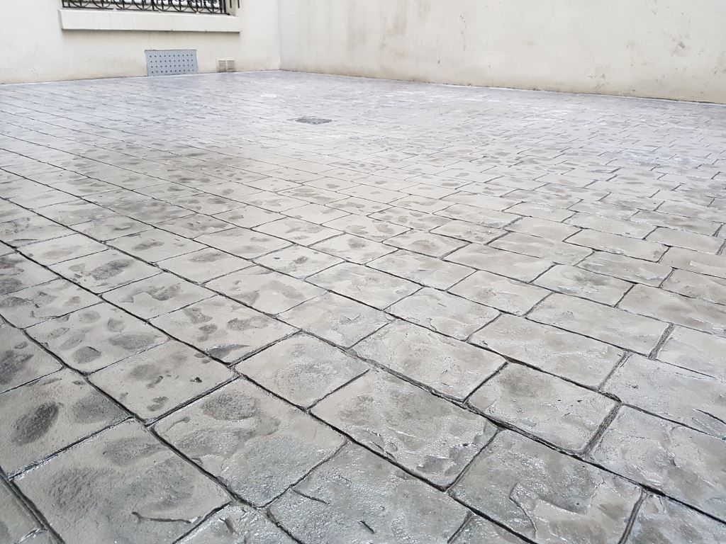 Béton imprimé au motif de briques coulées dans terrasse intérieure.