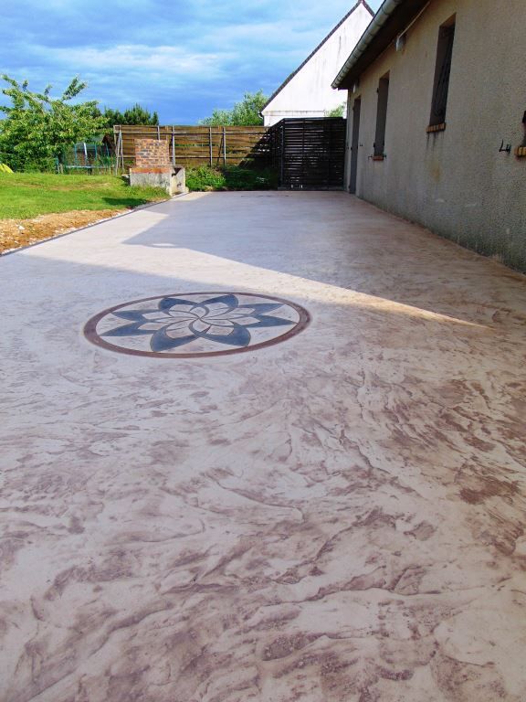 Superbe coulée de béton rougeâtre avec motif en forme de rosace sur passage extérieure à une maison.