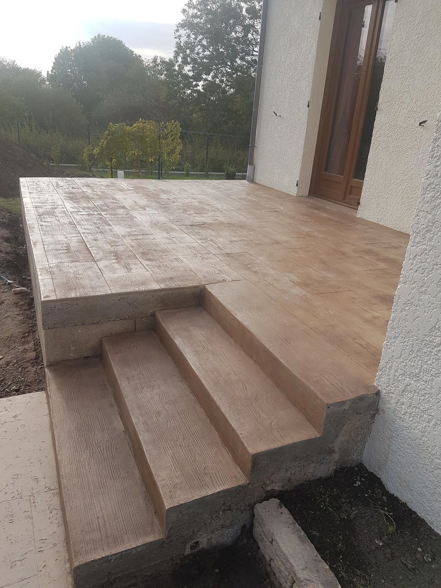 Terrasse en béton imprimé motif planches de bois marron.