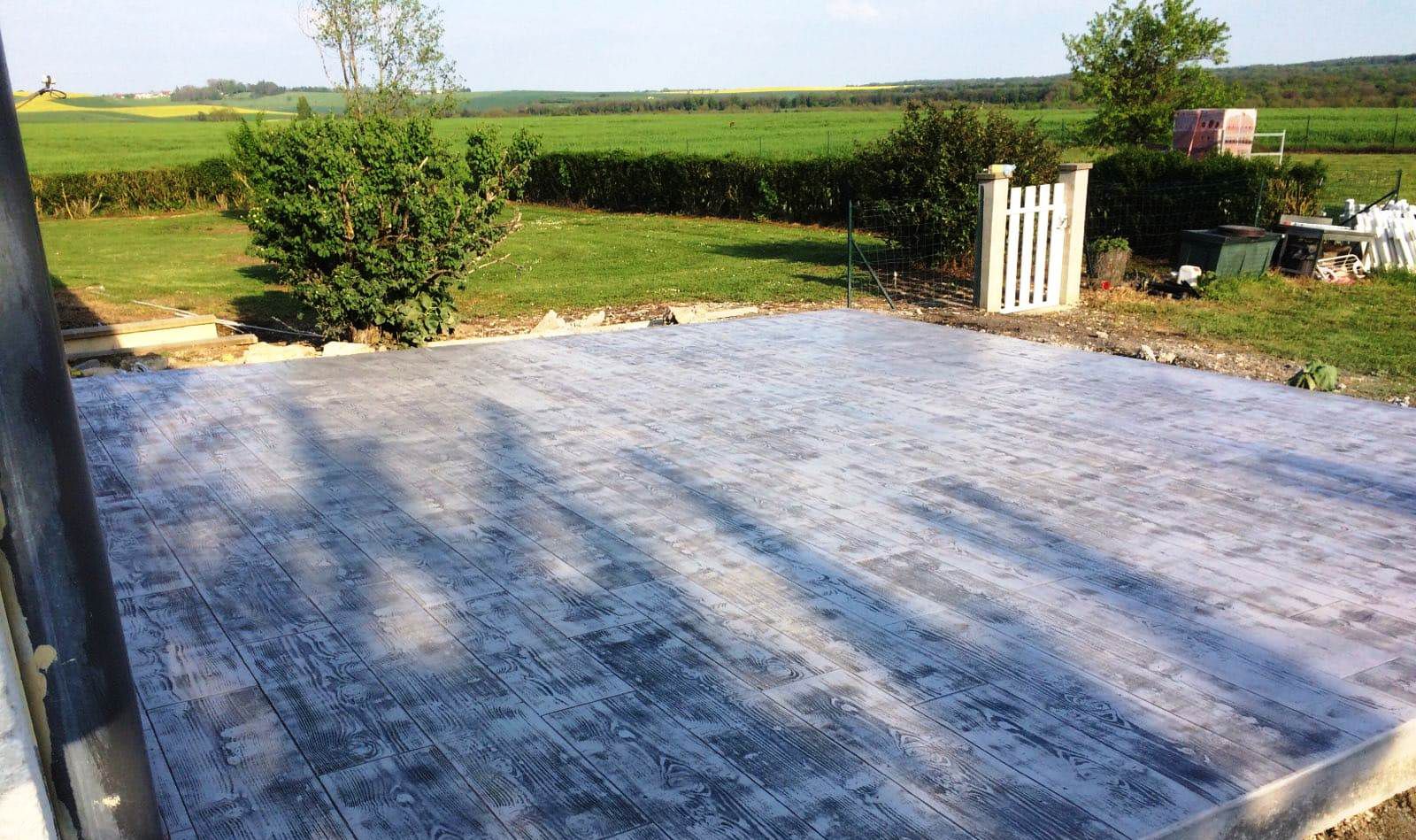 Terrasse extérieure en béton imprimé gris anthracite motif planches de bois.