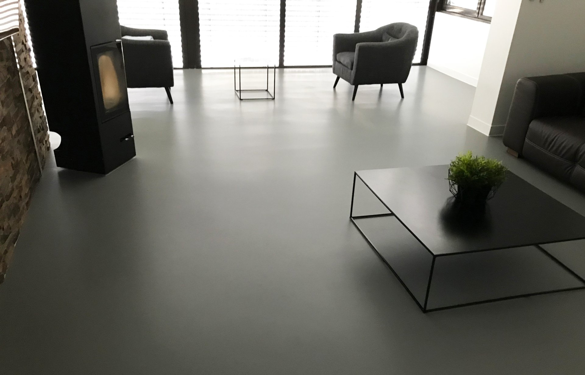 Béton ciré synthétique dans salle d'attente 'une entreprise avec fauteuil noir se faisant face et petite table basse.