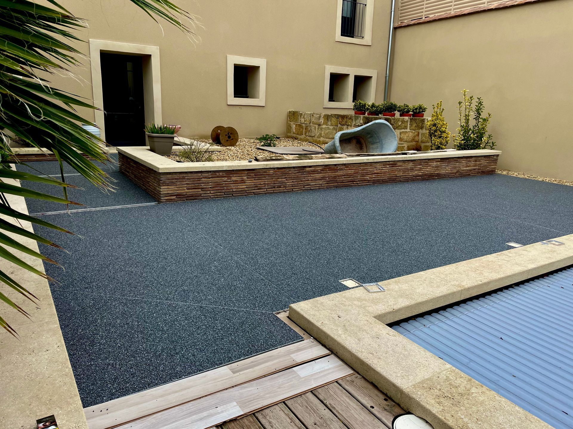 Terrasse en gravier avec mobilier de jardin et piscine couverte d'une bâche.