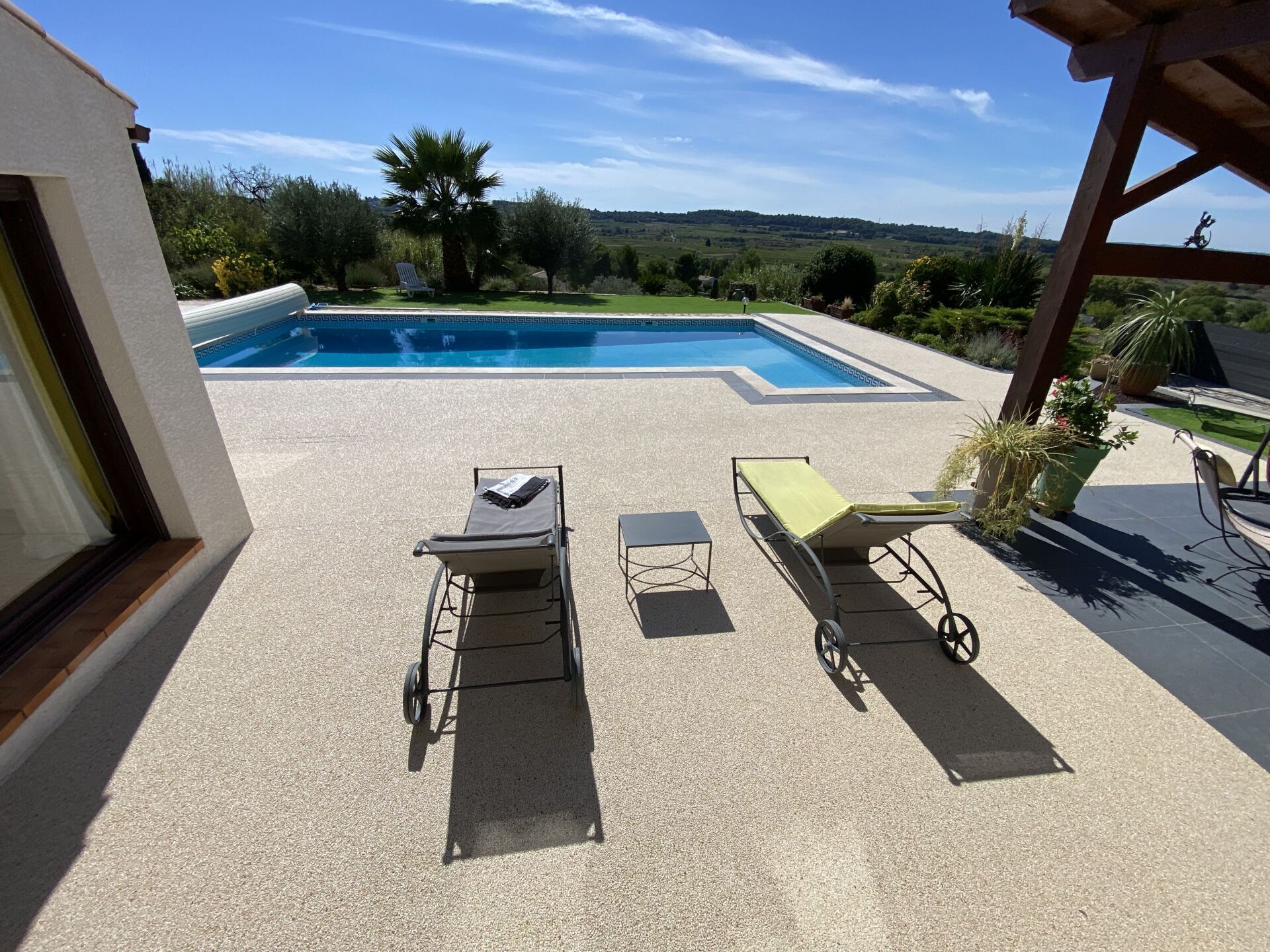 Extérieur en résine drainante, piscine creusée avec vue sur la vallée et transats orientés plein soleil.
