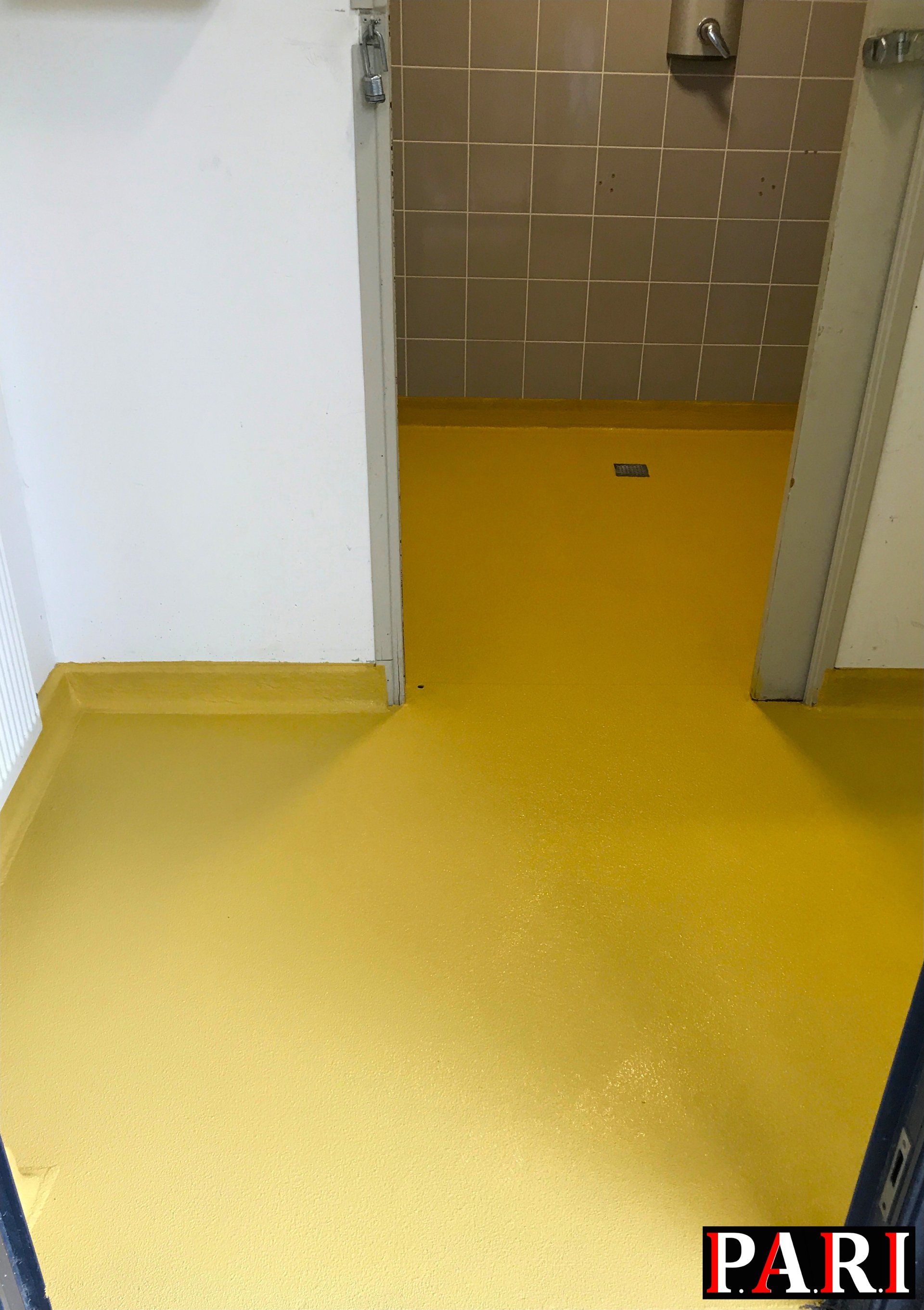 Résine drainante coulée autour d'une piscine creusée dans propriété moderne avec herbe synthétique et panneaux photovoltaïques sur le toit.