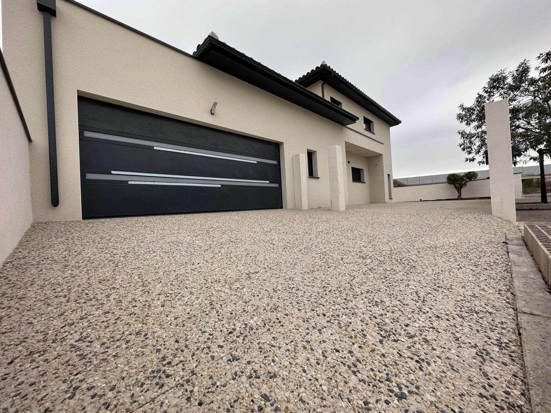 Moquette de pierre de couleur beige devant un garage et une maison.
