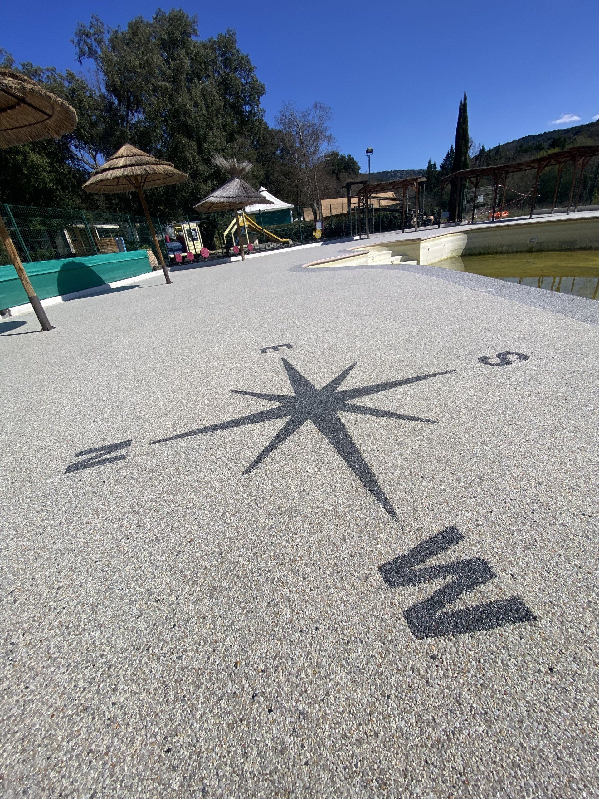 Surface en gravier beige avec un motif en étoile formé par des ombres.