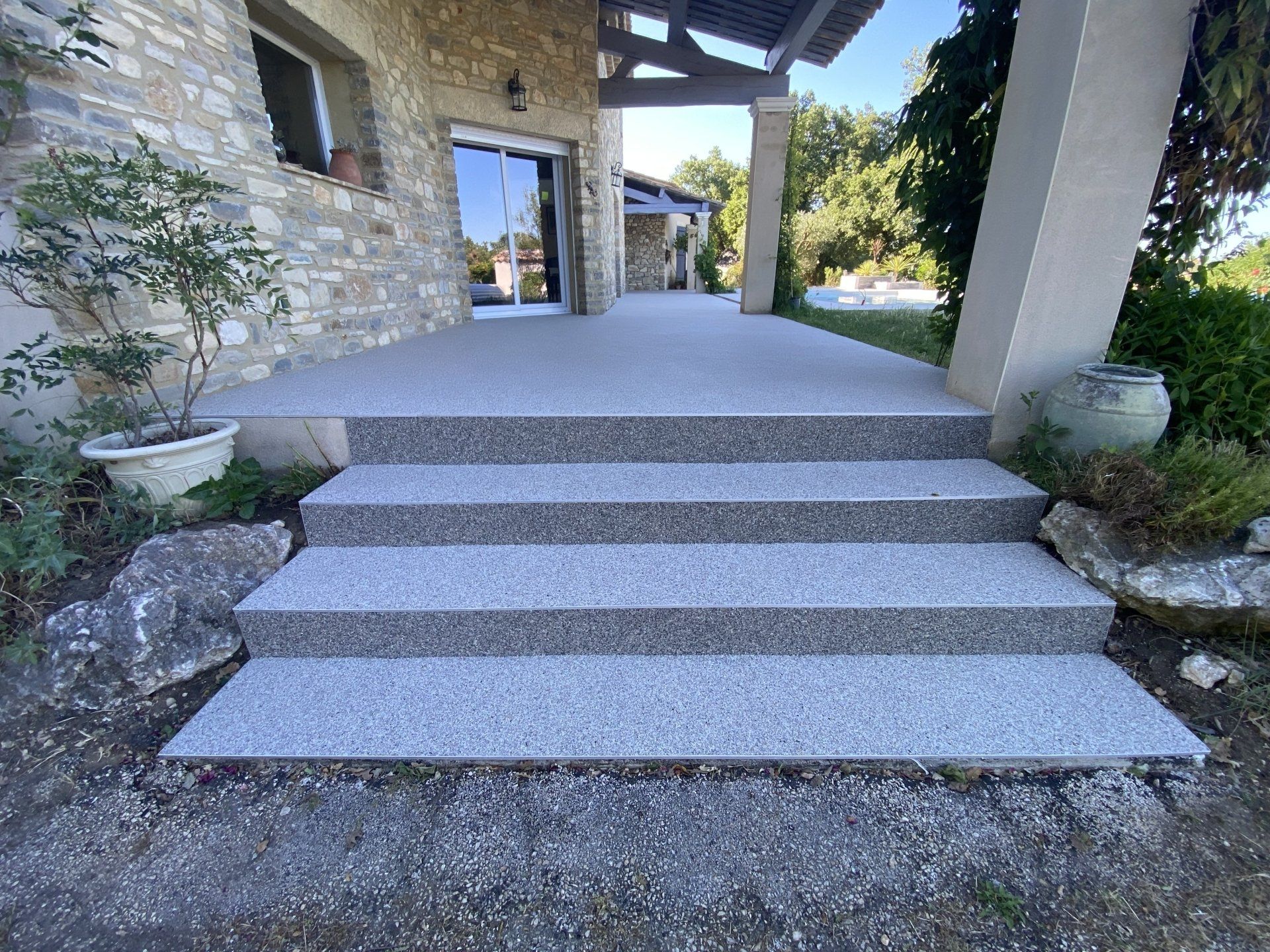 Escalier en gravier beige avec des marches en béton menant à une entrée de maison.
