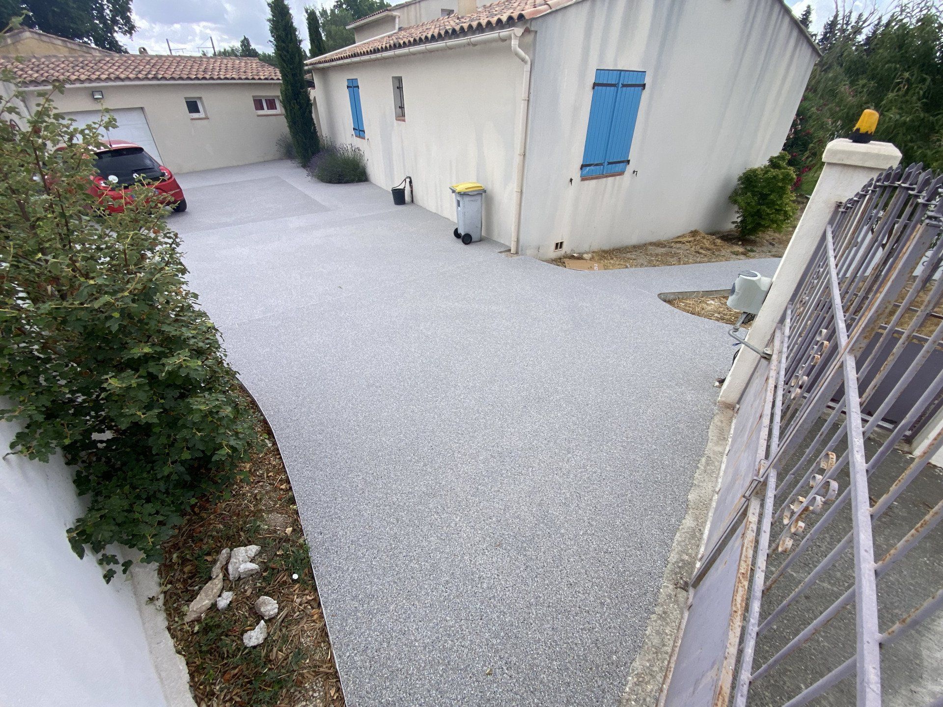 Allée en gravier blanc avec des bordures en pierre et des plantes vertes.