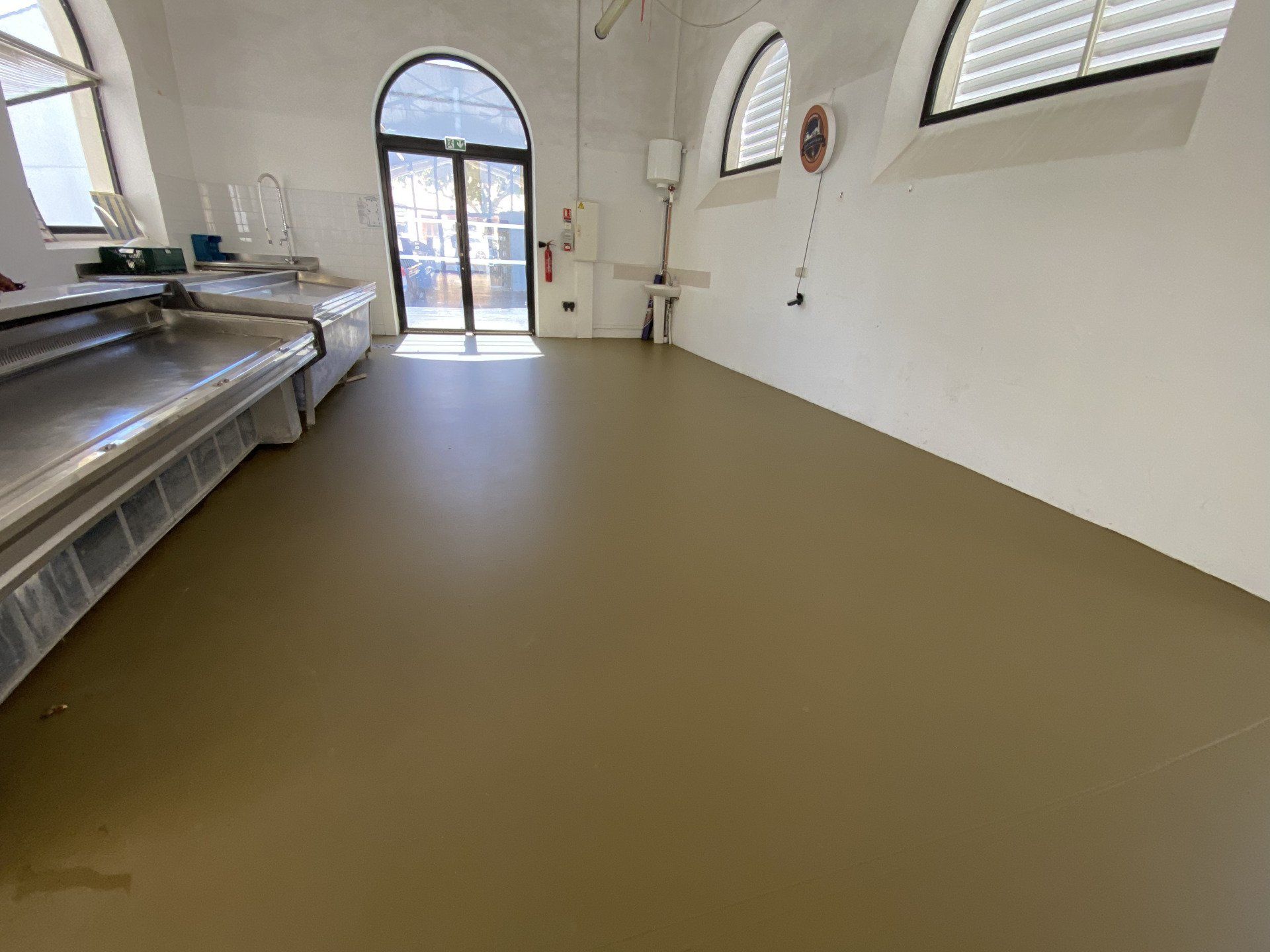 Sol en résine marron dans un espace intérieur avec des équipements industriels.