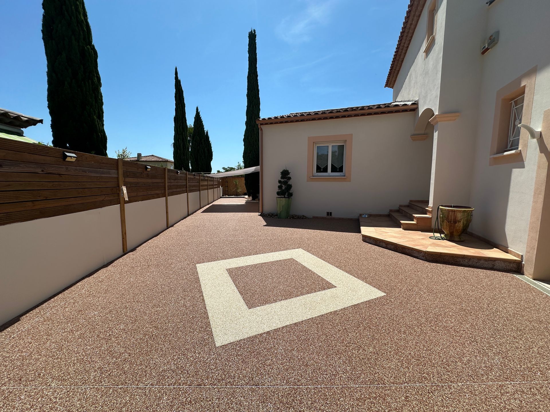 Entrée de maison avec revêtement en résine orné d'un motif carré blanc.