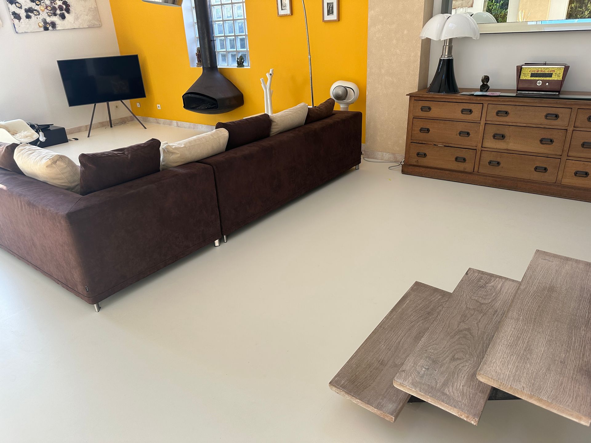 Salon contemporain avec sol en résine clair, mobilier moderne et murs colorés.