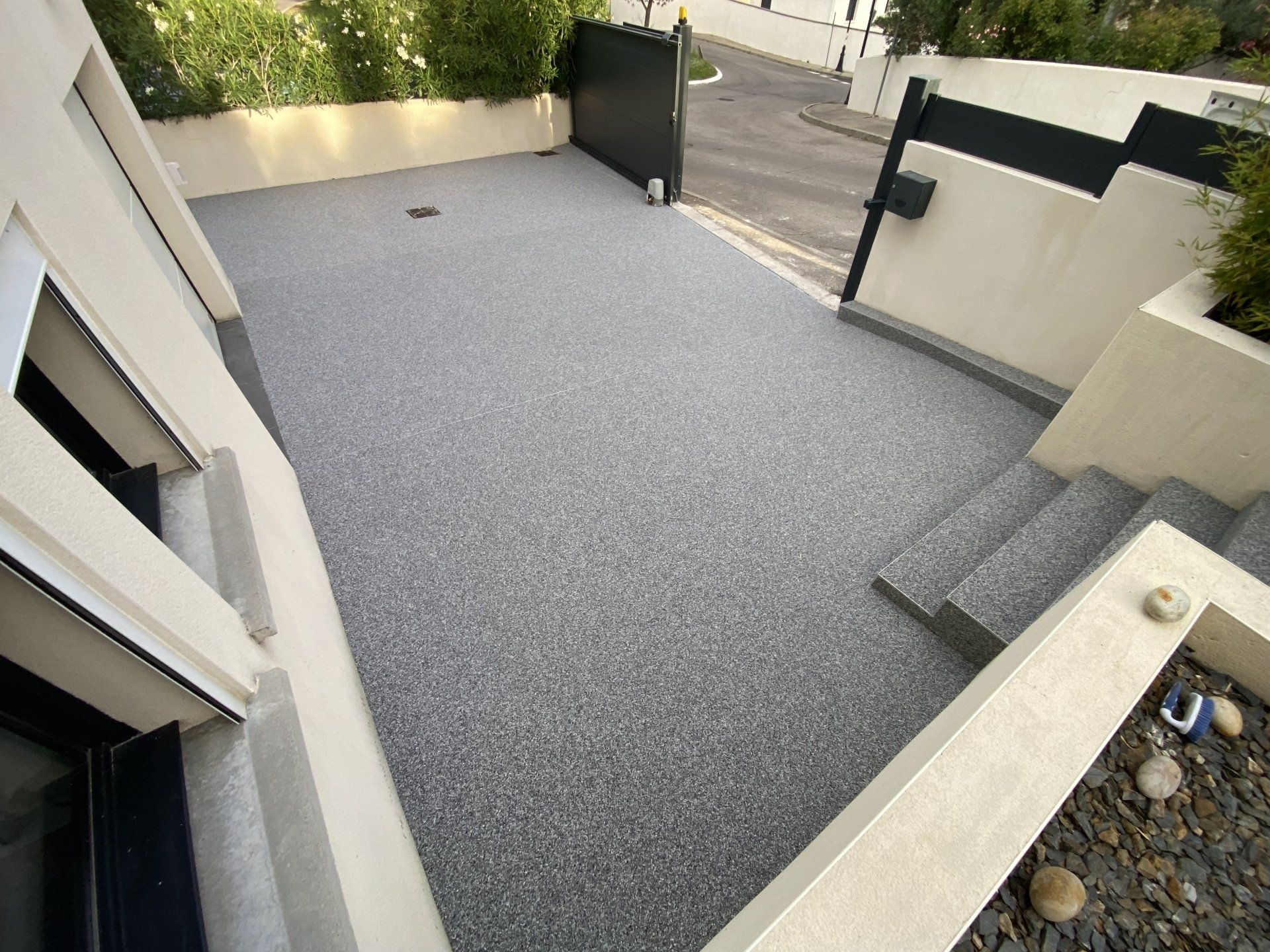 Terrasse en gravier gris avec des bordures en bois et une vue sur un jardin.