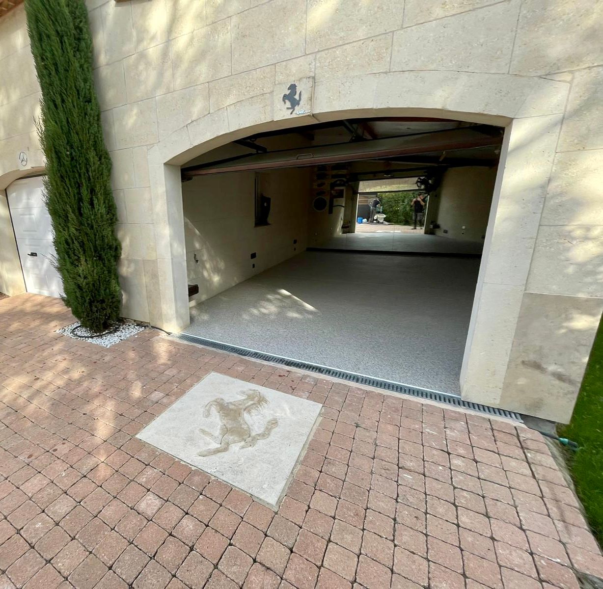 Allée couverte en béton avec des murs blancs et un sol en damier avec un grand carrelage avec un cheval en décoration.