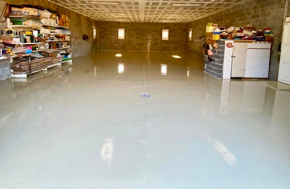 Grand espace intérieur avec un sol en résine brillante, éclairé par des lumières artificielles.