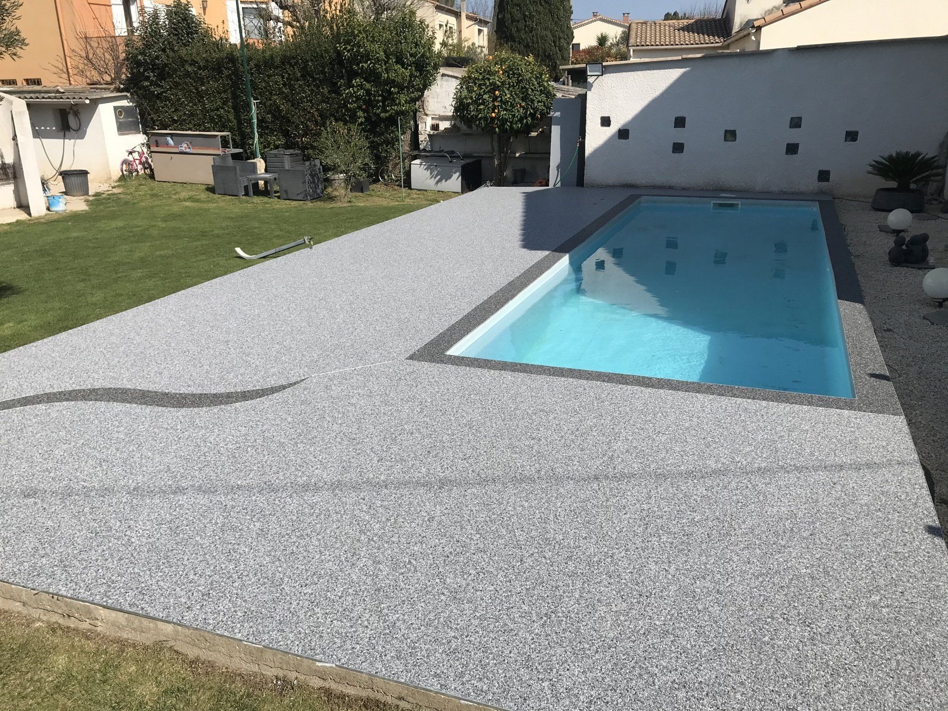 Résine décorative avec motif gris anthracite coulée devant piscine creusée.