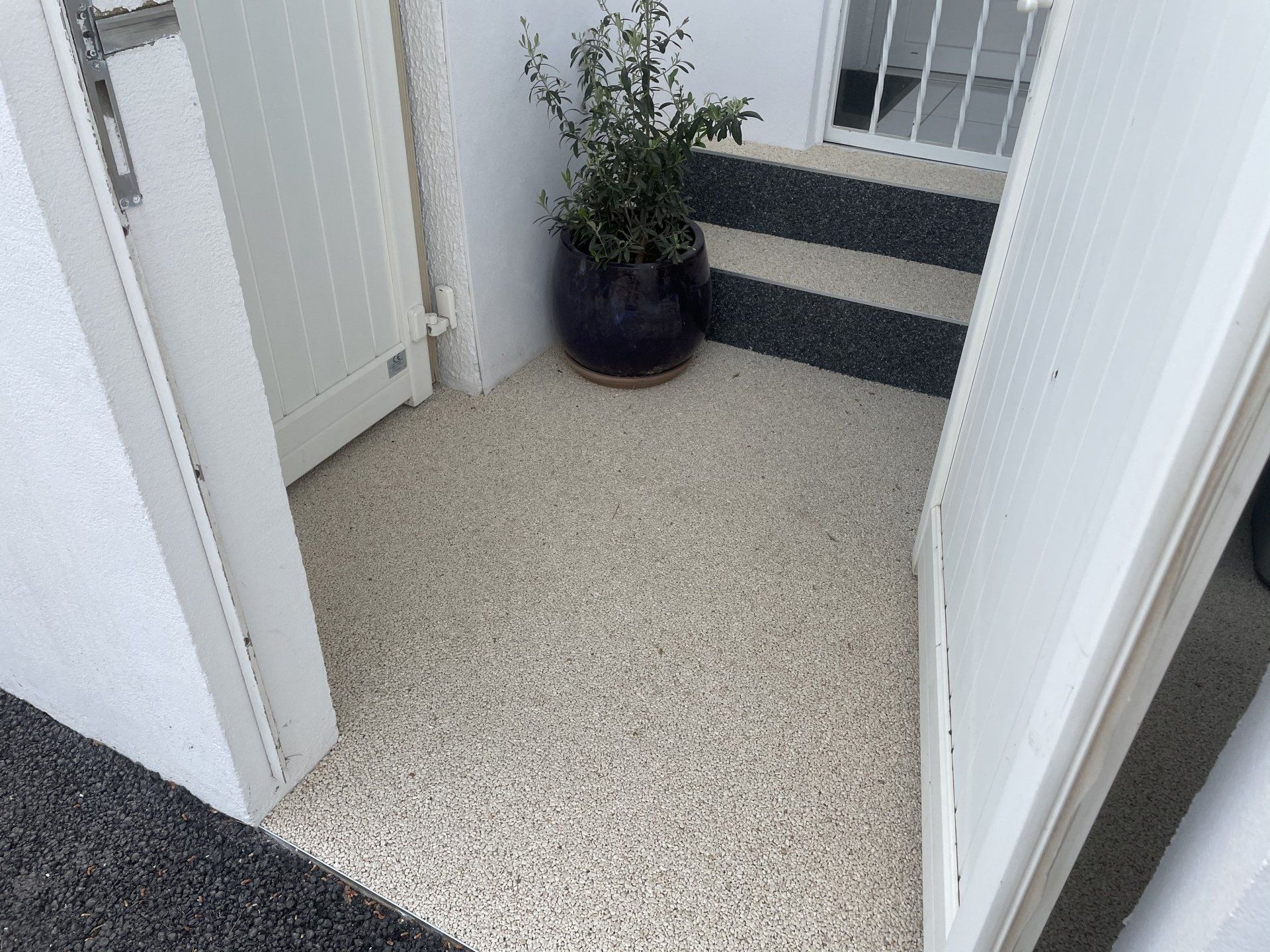 Résine drainante bicolore coulée dans petite entrée de maison avec marches.