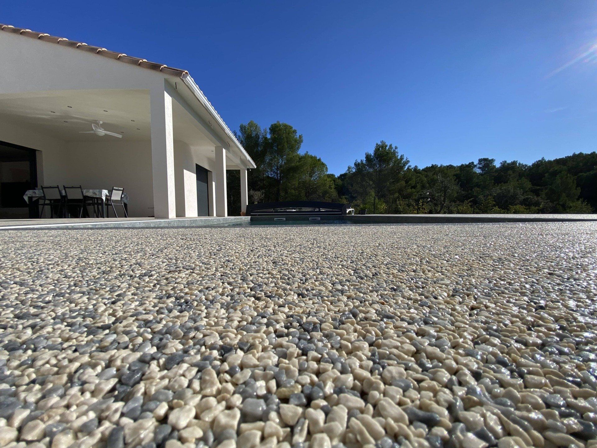 Résine drainante en gros plan, vu superbe sur les matériaux et maison en fond.