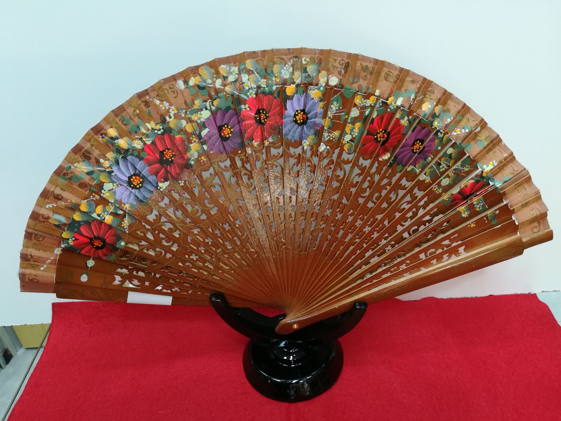 Un abanico de madera con flores pintadas.
