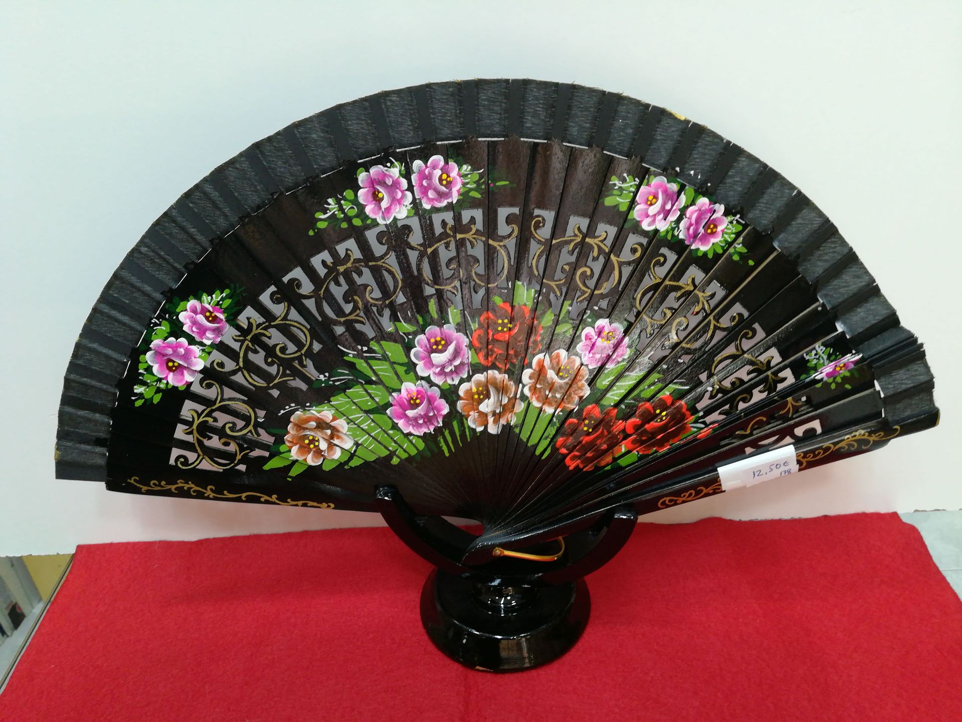 Un abanico negro con flores pintadas.