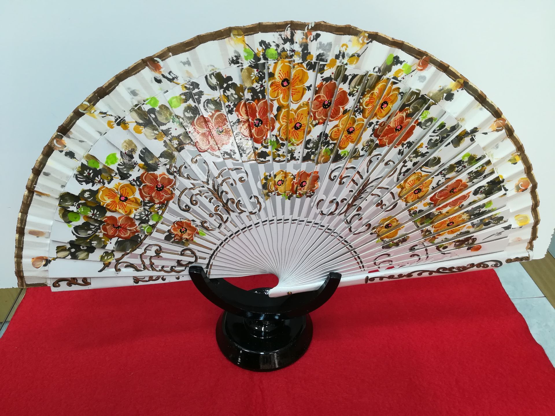 Un abanico con flores está sobre un soporte.