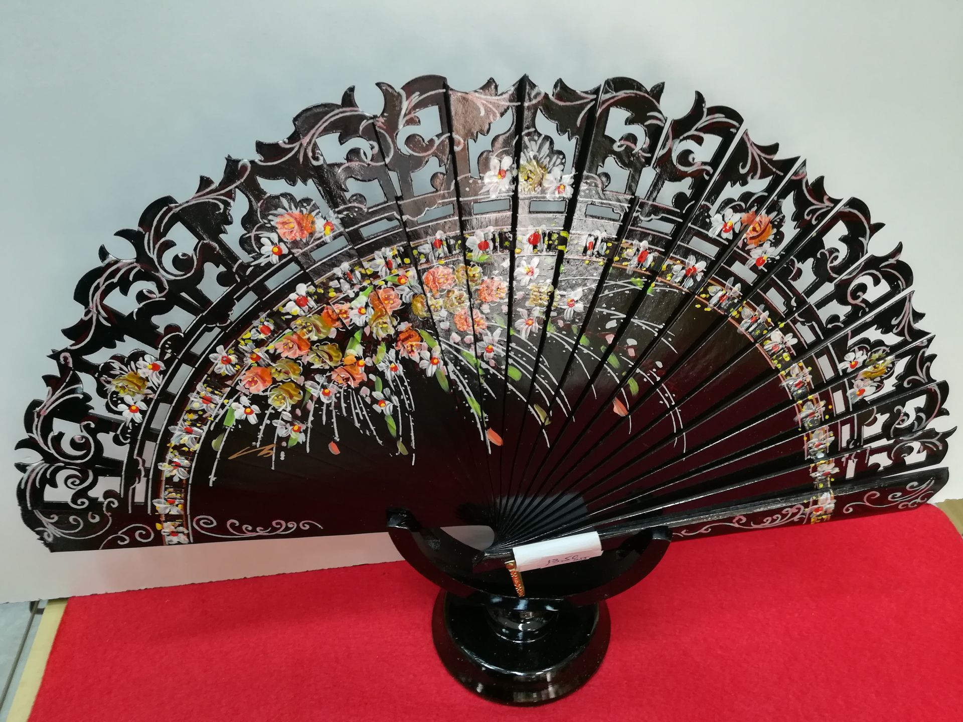 Un abanico negro con flores se encuentra sobre una alfombra roja.