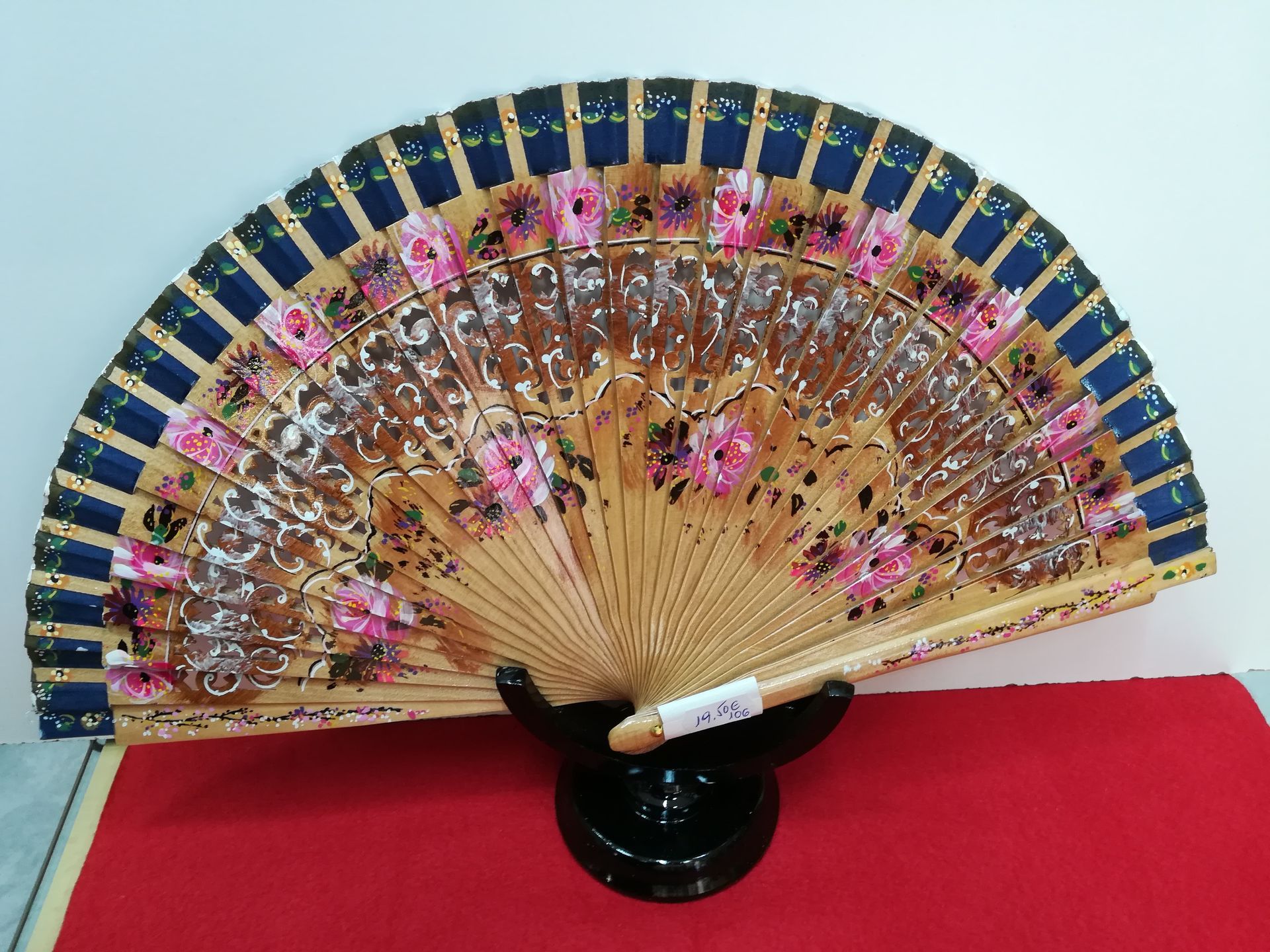 Un abanico con flores está sobre una mesa.