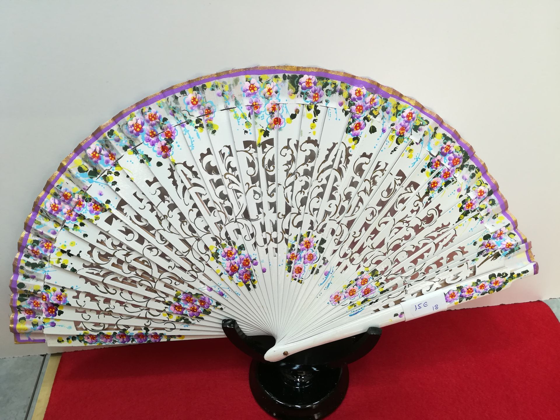Un abanico blanco con flores moradas.