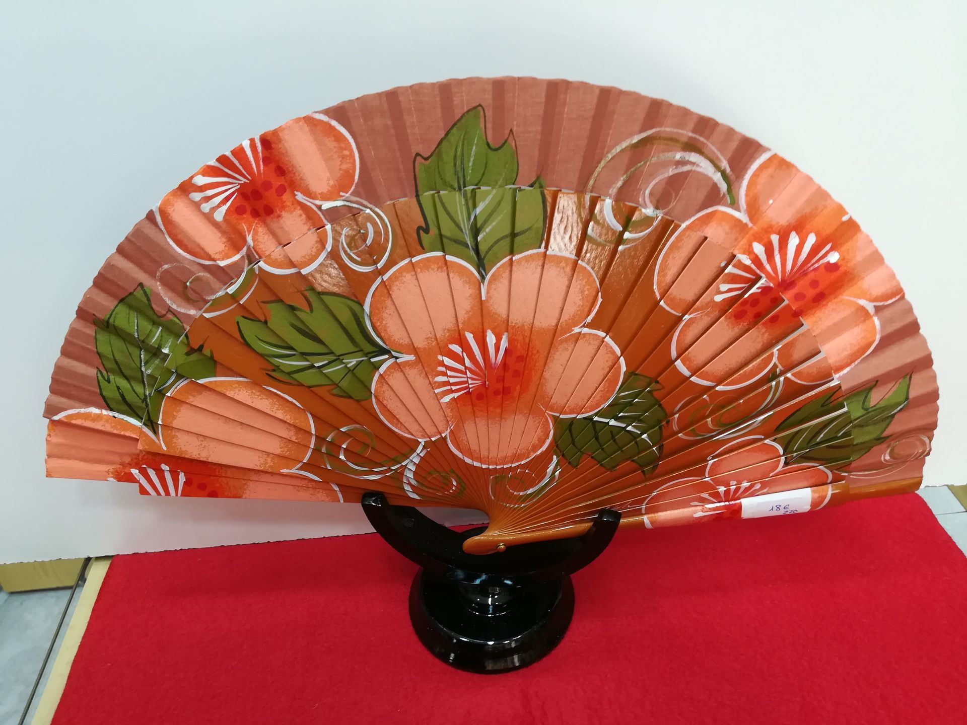 Un abanico con flores y hojas pintadas.