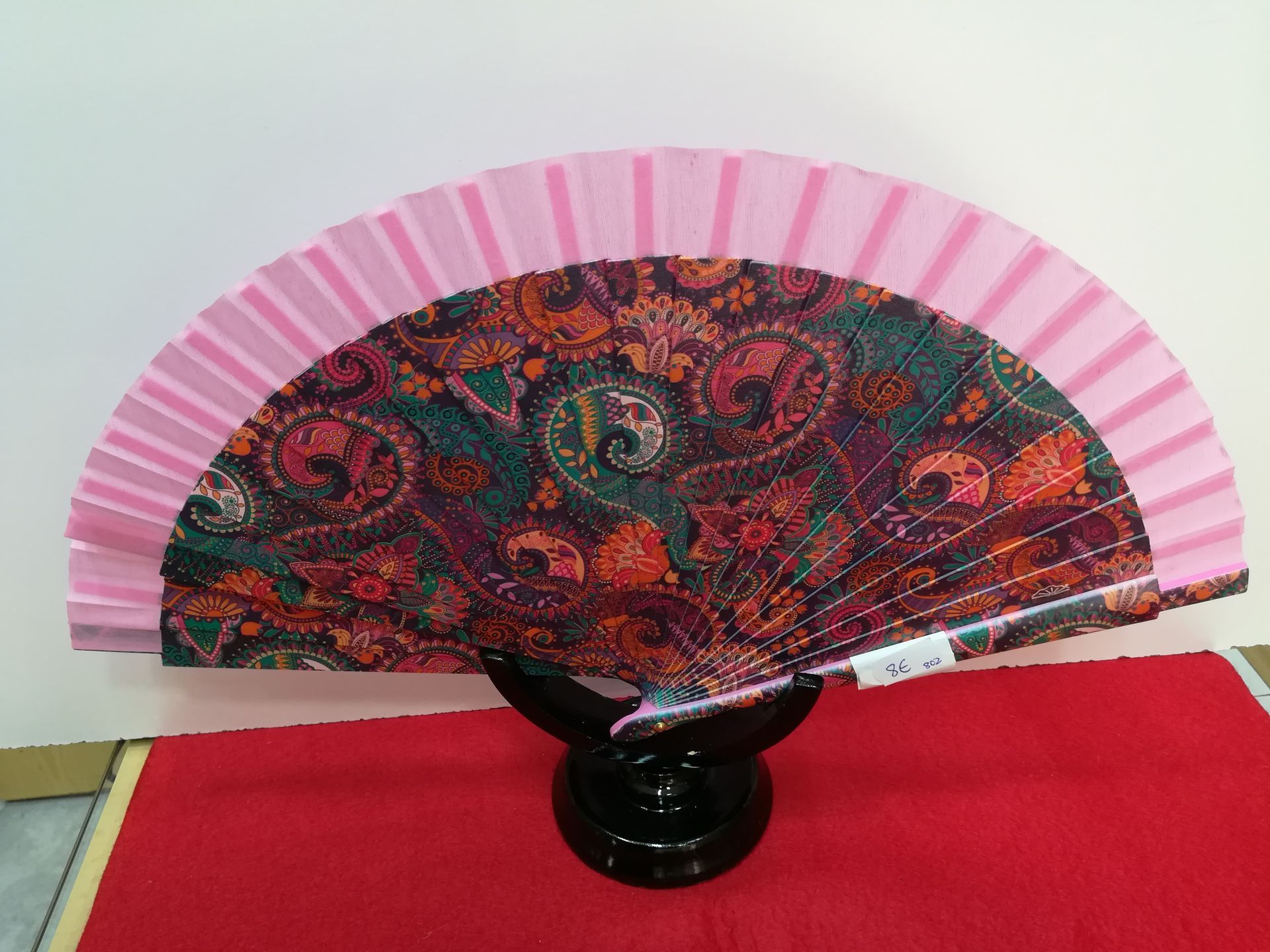 Un abanico rosa con un estampado paisley.