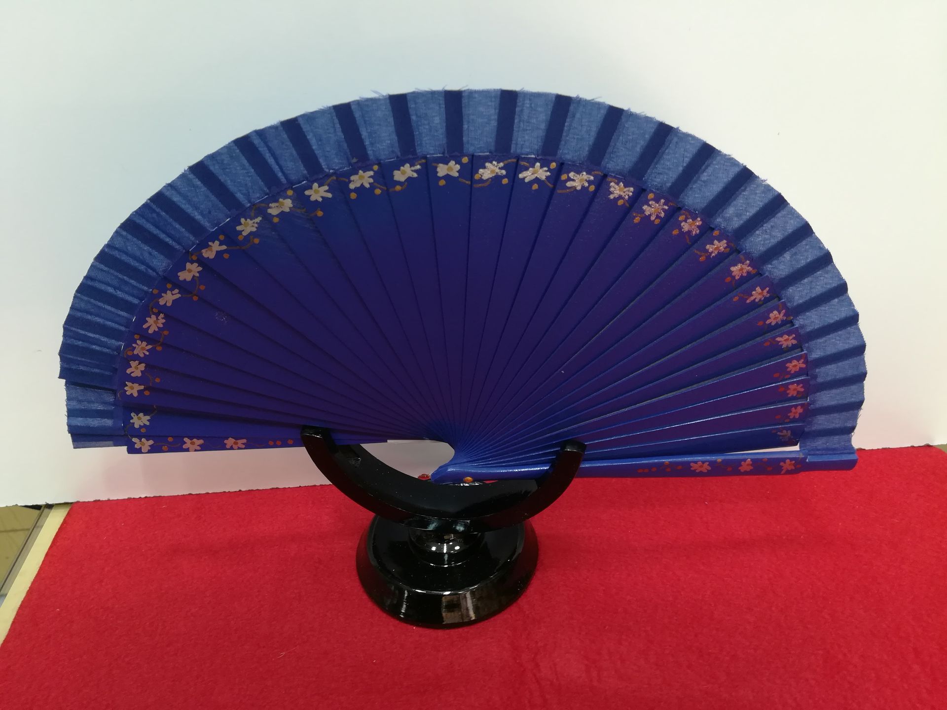 Un ventilador azul está sentado en un soporte negro