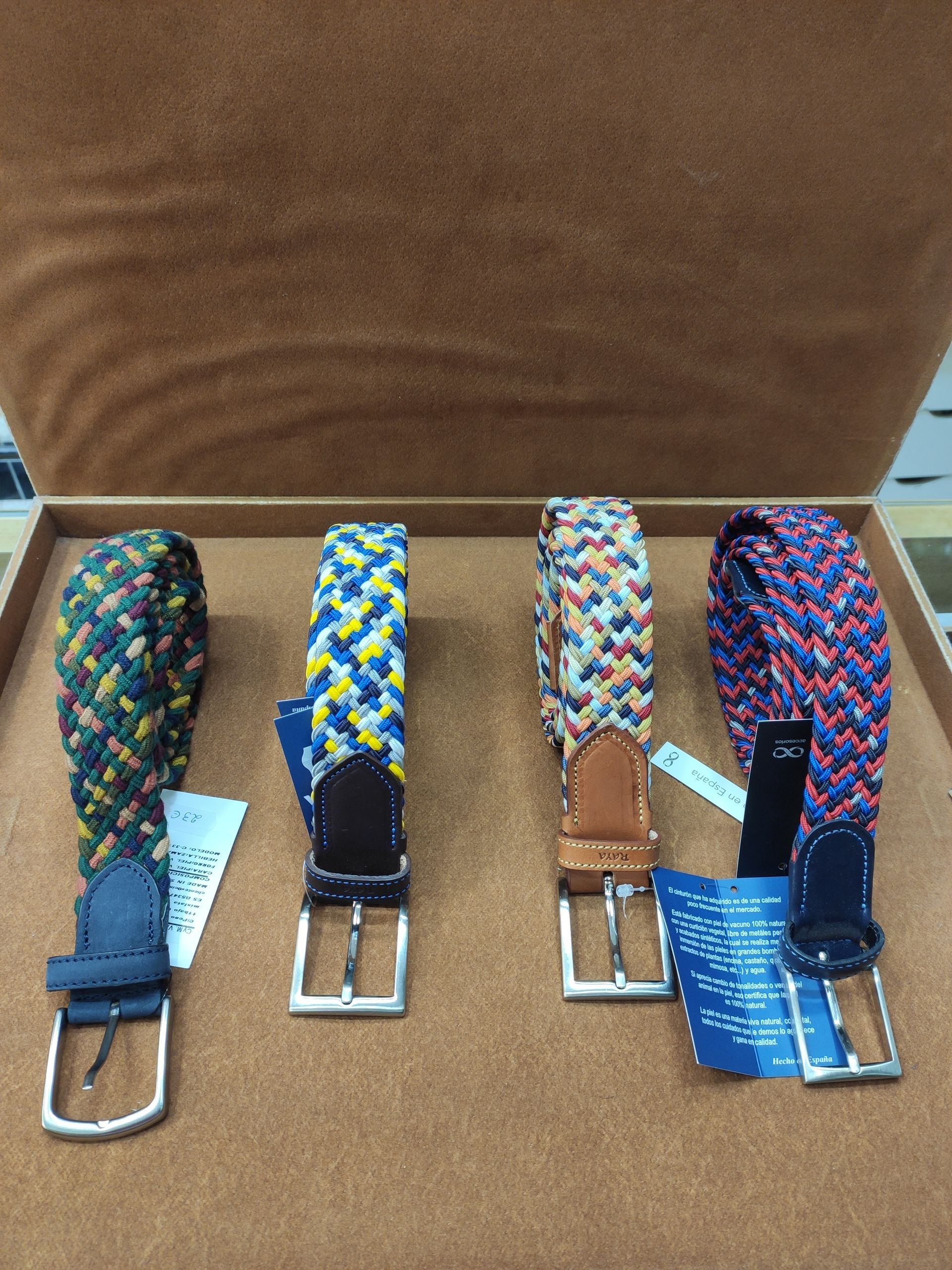 Cuatro cinturones de diferentes colores están alineados en una caja.