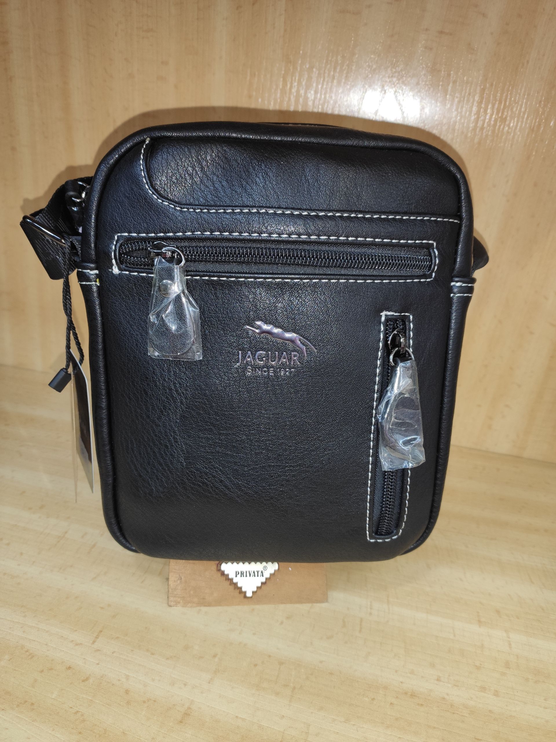 Una pequeña bolsa negra está sobre una mesa de madera.