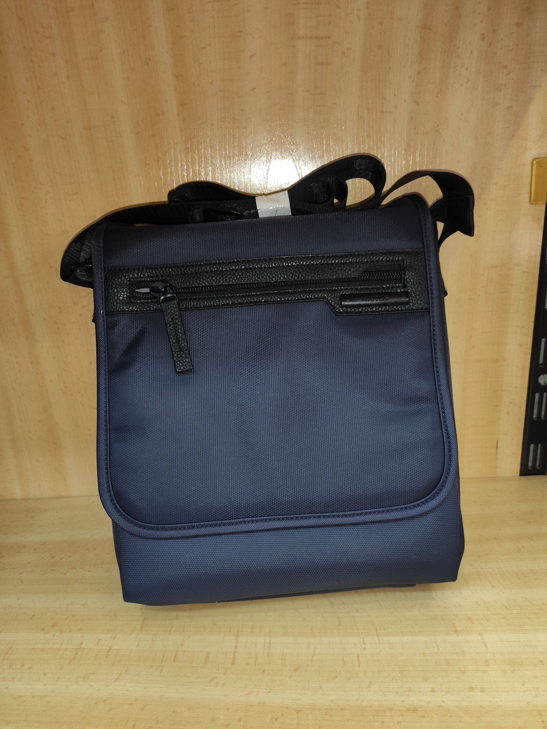 Una pequeña bolsa negra está sobre una mesa de madera.