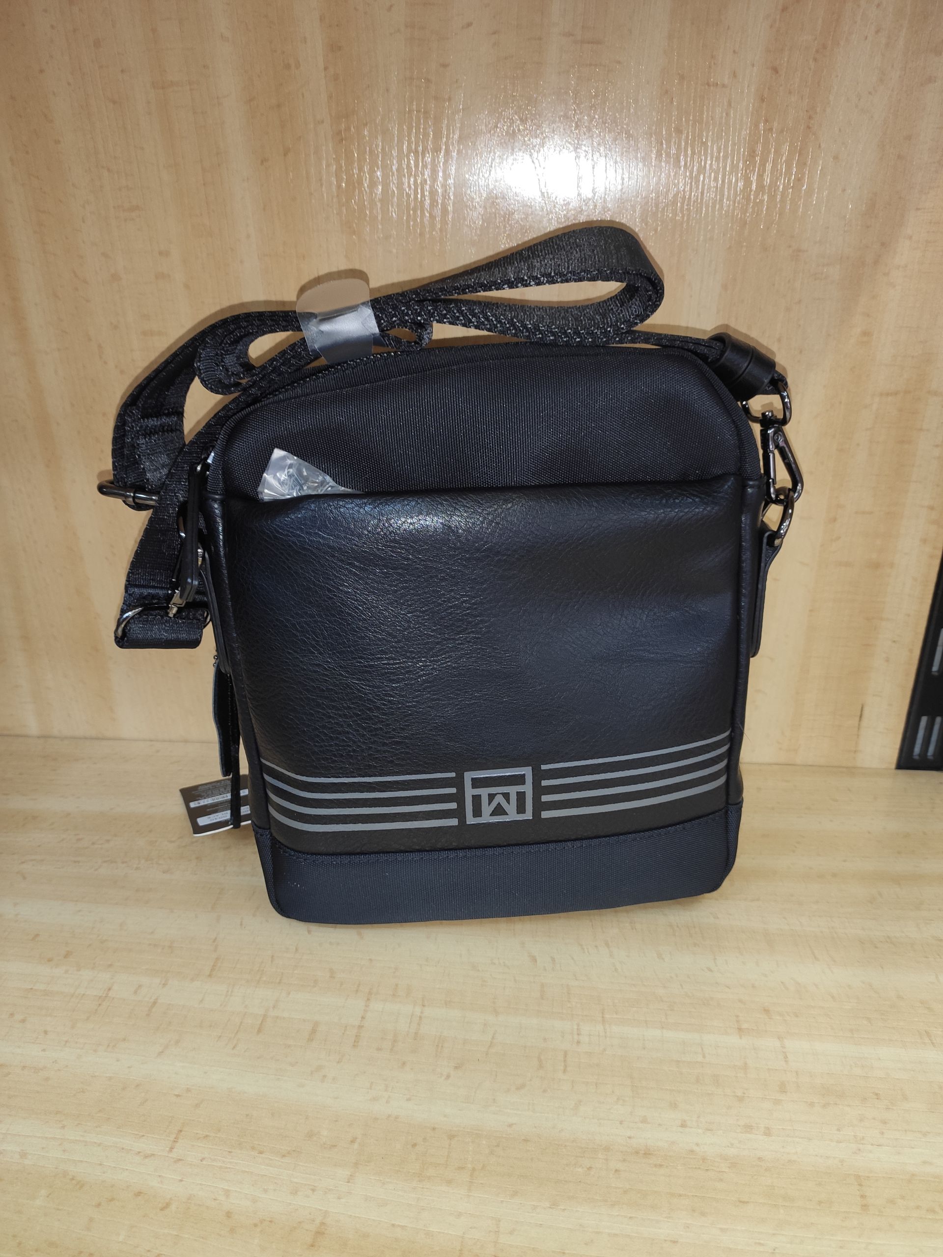 Una pequeña bolsa negra está sobre una mesa de madera.