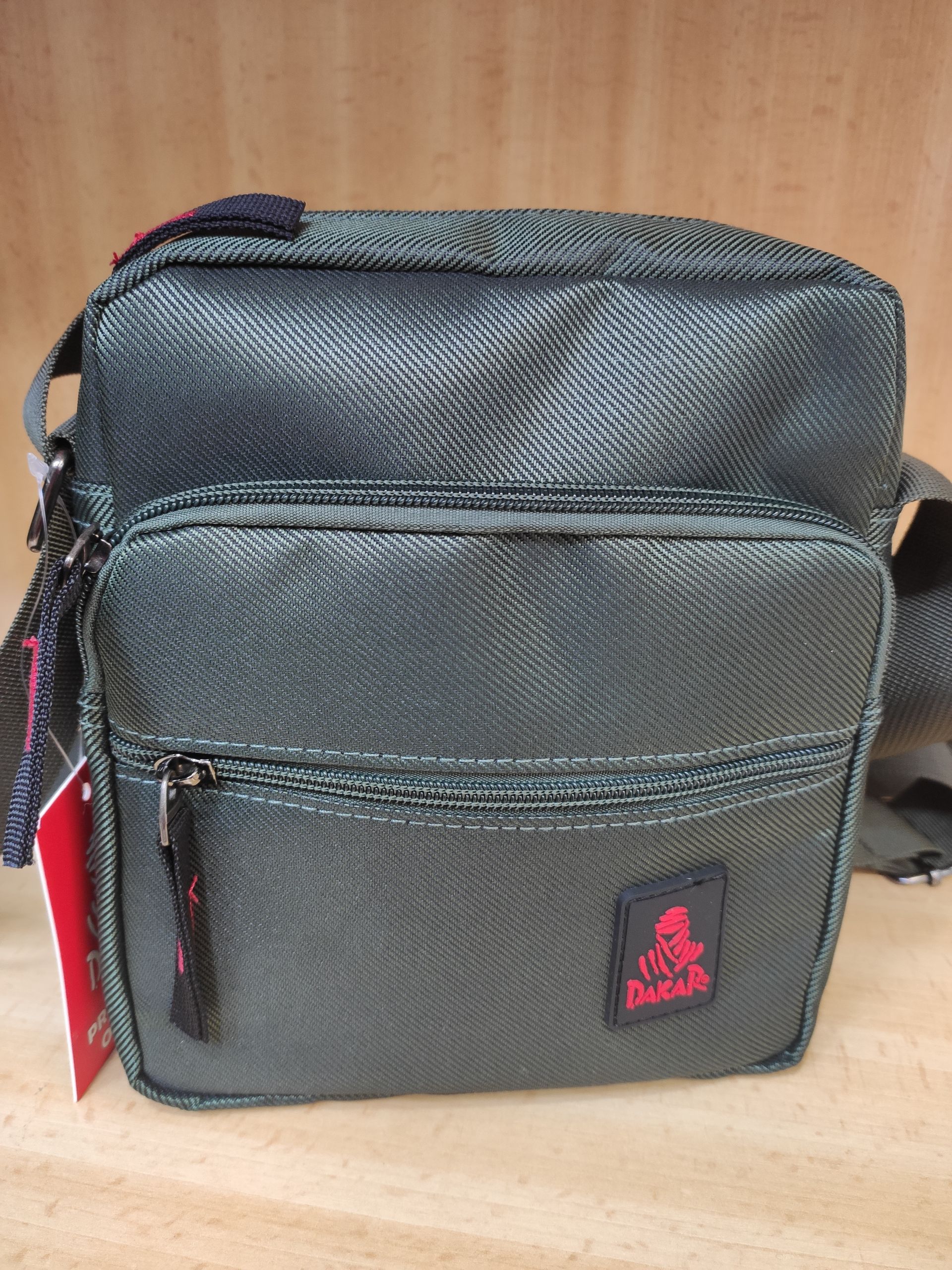 Una pequeña bolsa negra con un logo rojo está sobre una mesa de madera.