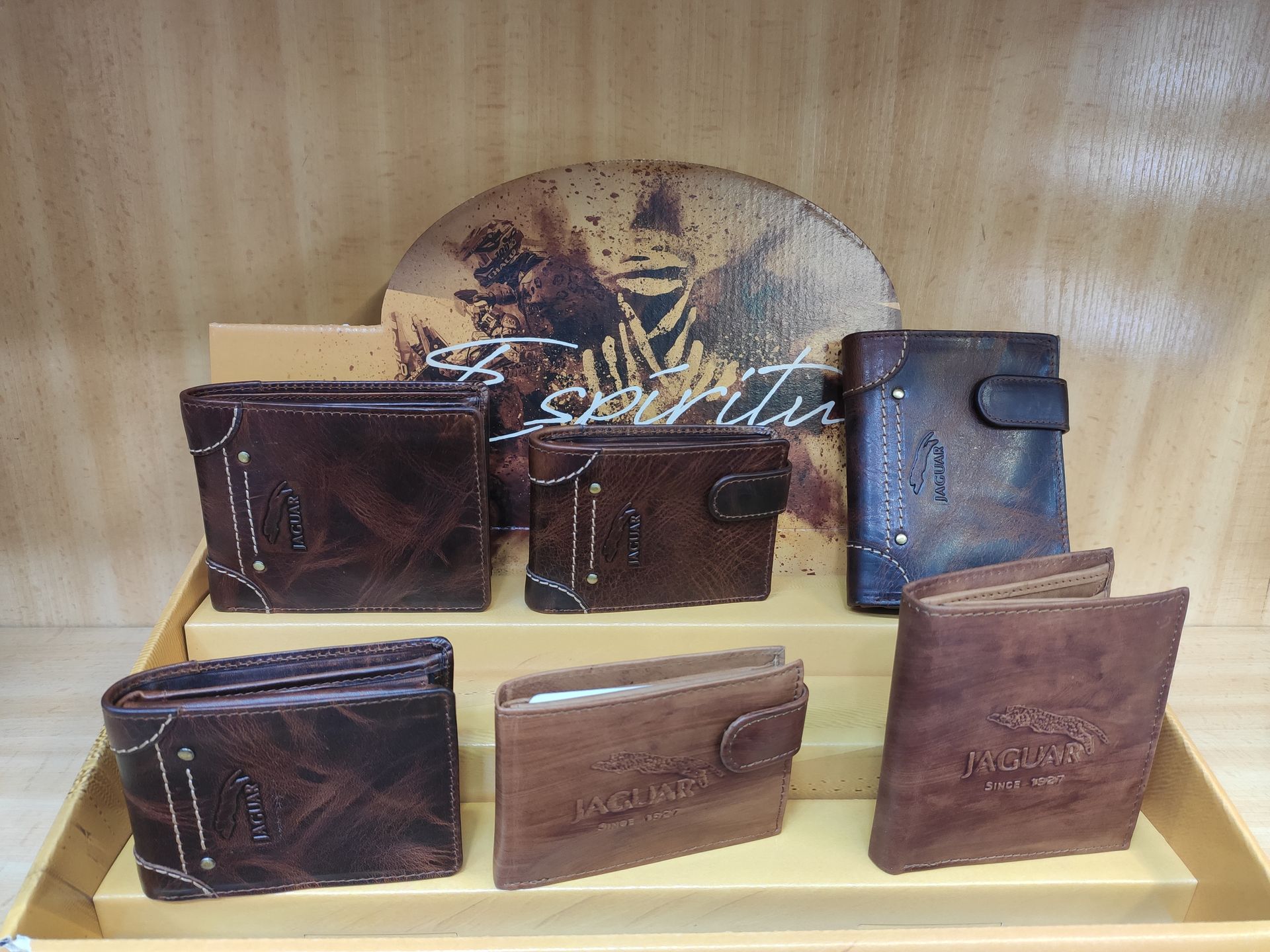 Una exhibición de carteras de cuero marrón en un estante de madera.