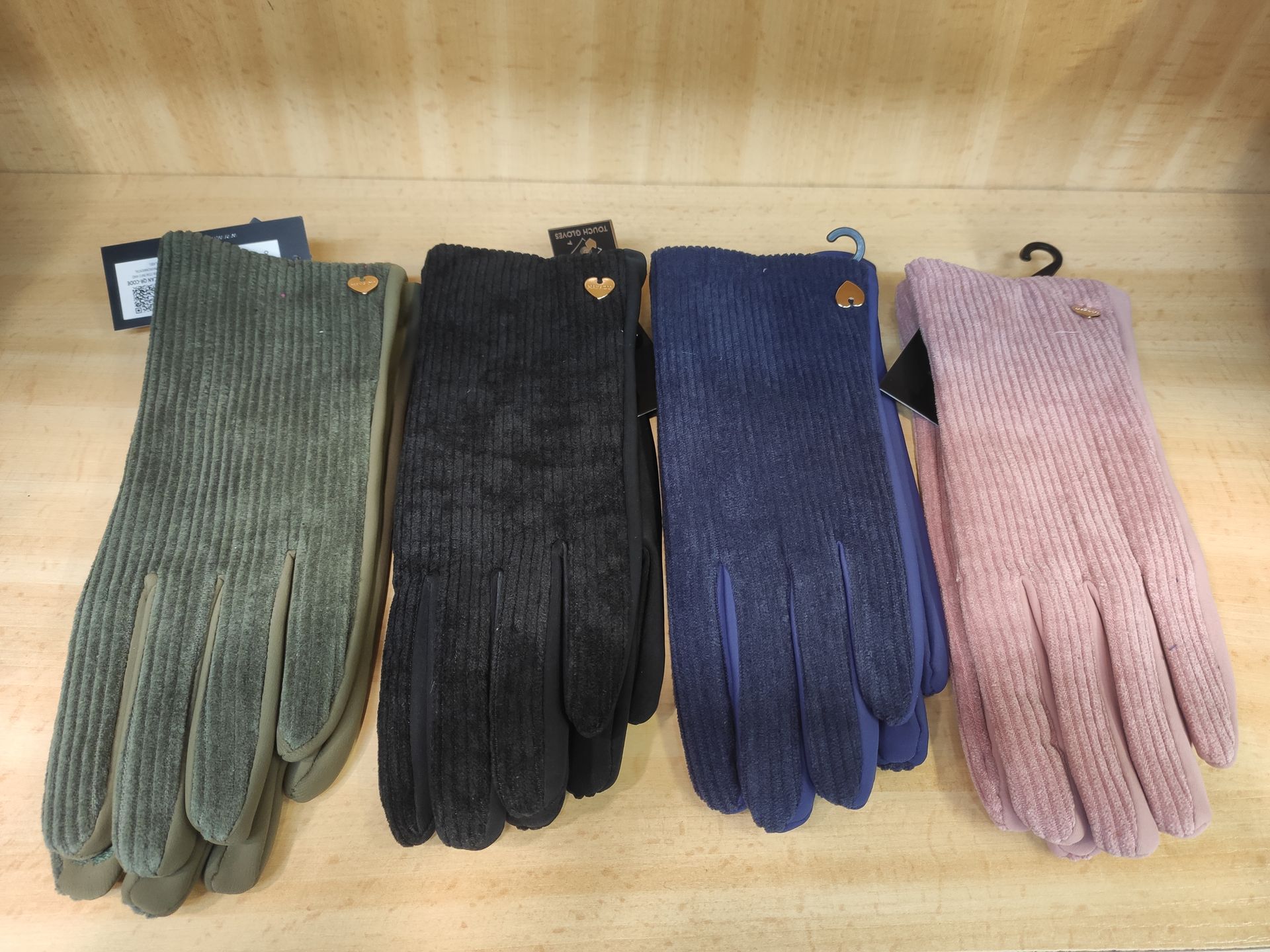 Una fila de guantes están alineados en un estante de madera.