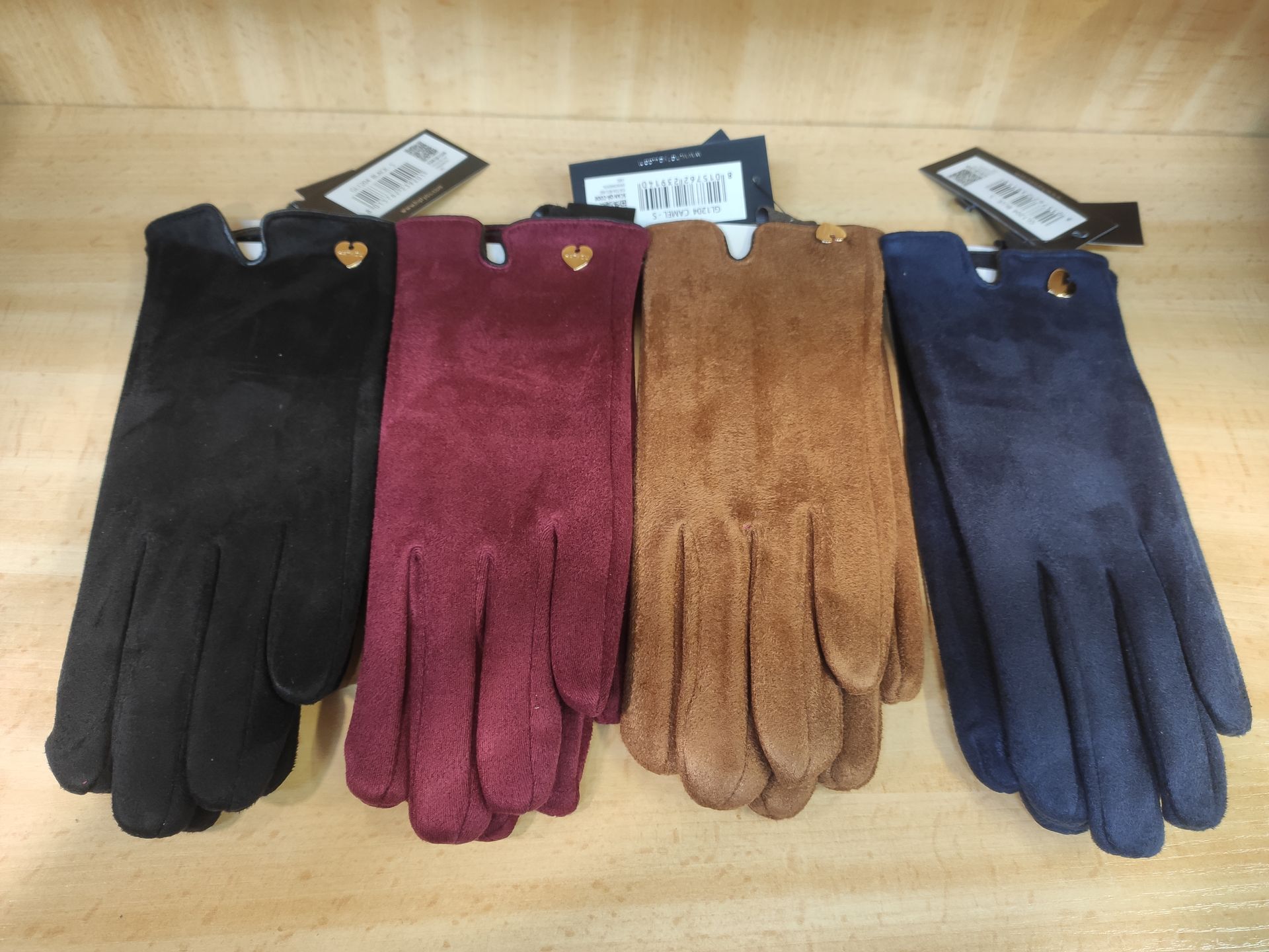 Cuatro guantes de diferentes colores están sobre una mesa de madera.