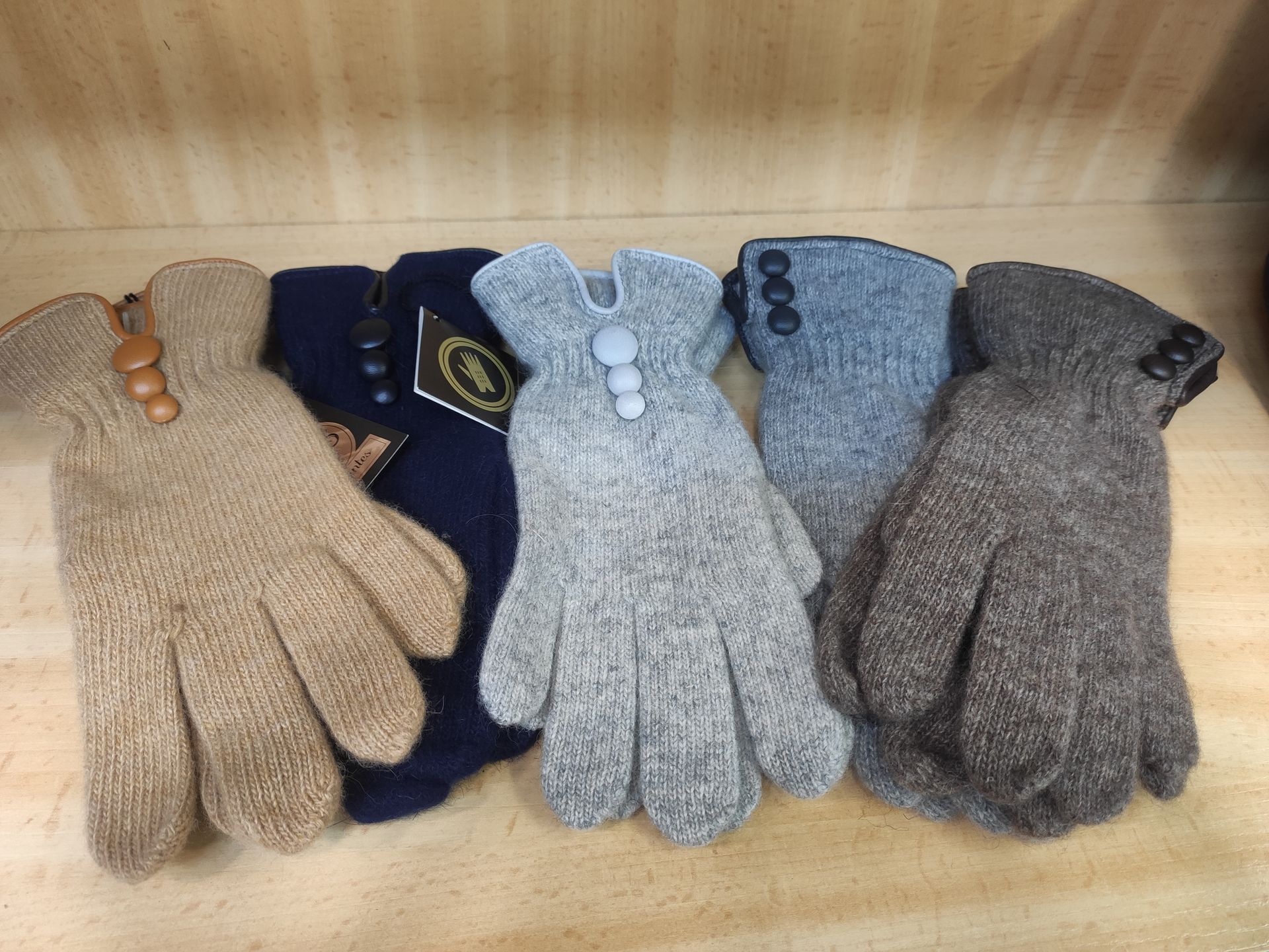 Un grupo de guantes están alineados sobre una mesa de madera.