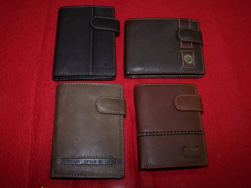 Cuatro carteras de cuero están alineadas sobre una tela roja.